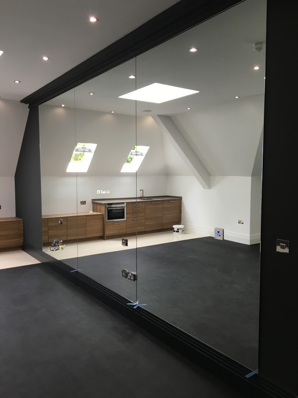 Frameless glass partition in loft conversion by Mill Hill glaziers